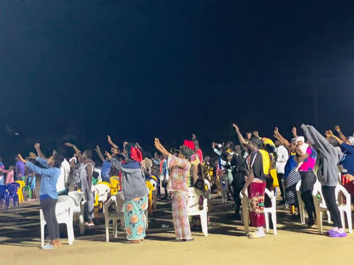 Congregation lifting hands in worship at night